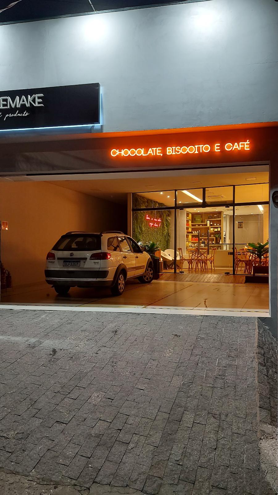 Fachada de doceria à noite com letreiro de neon aceso