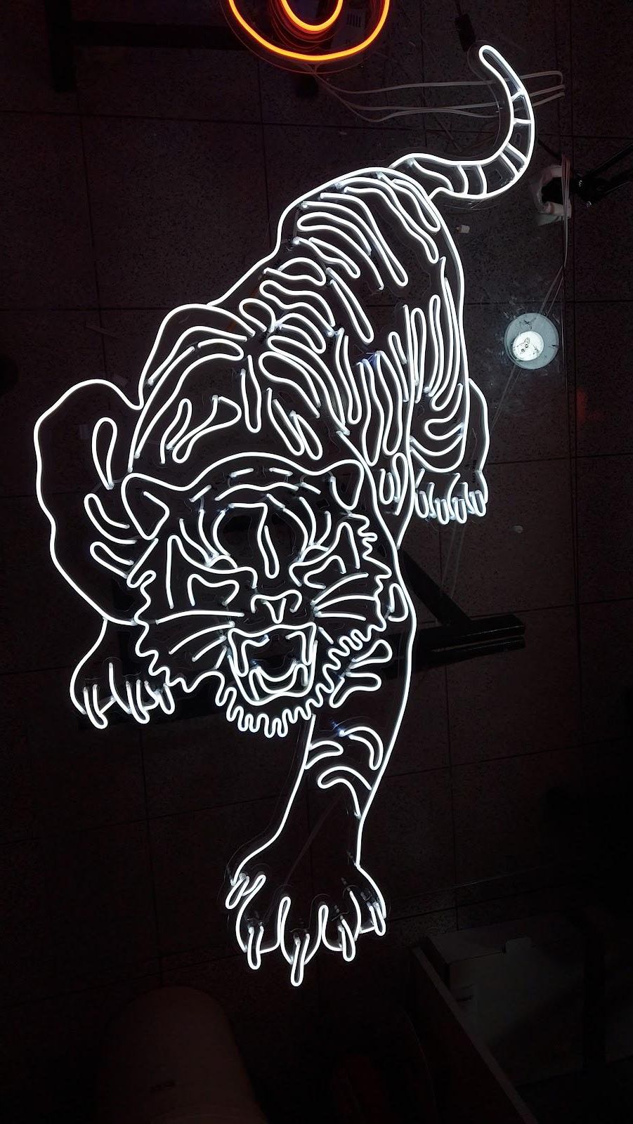 Neon branco em forma de tigre em parede escura de bar