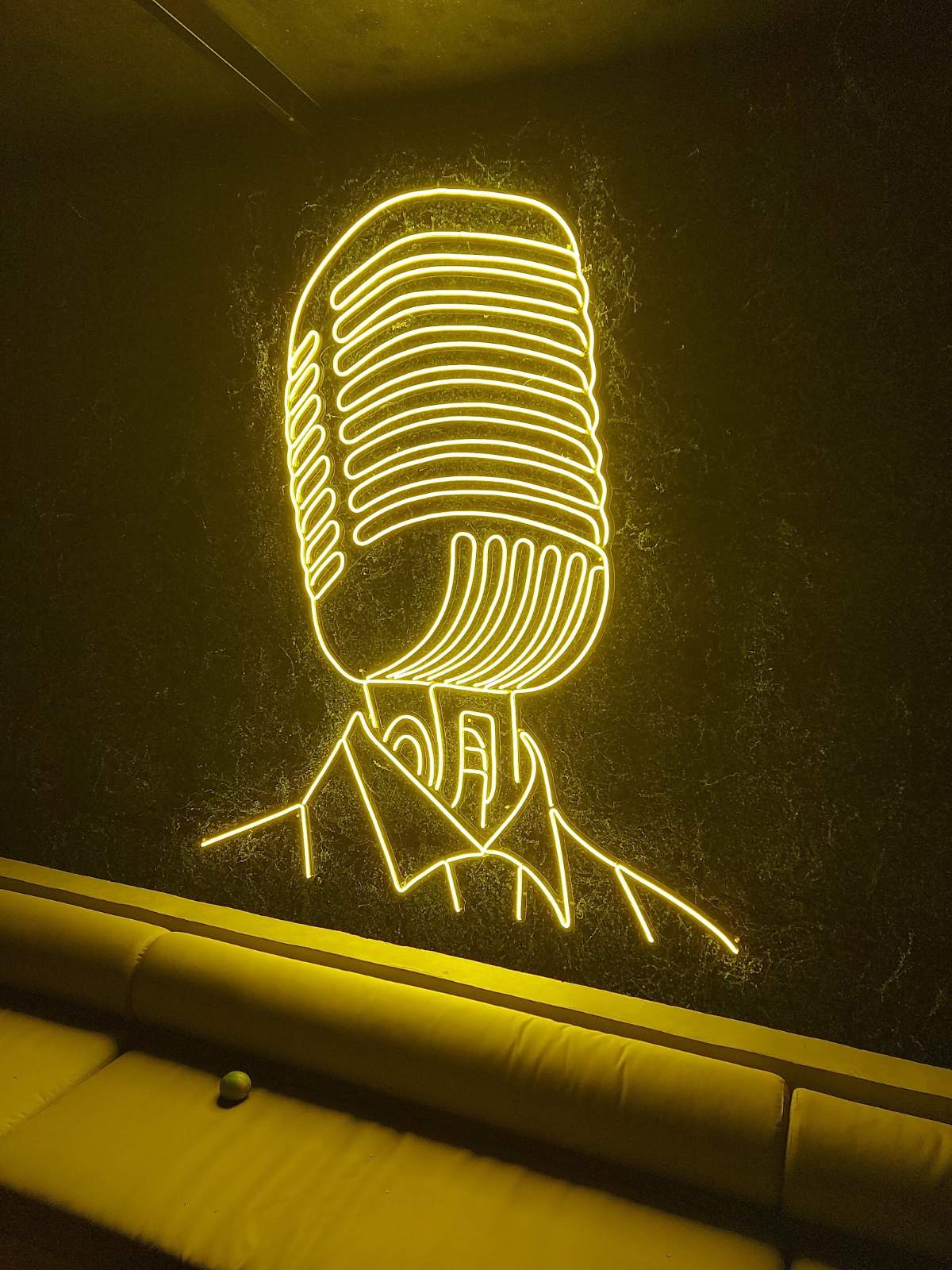 Neon amarelo de microfone em parede de bar