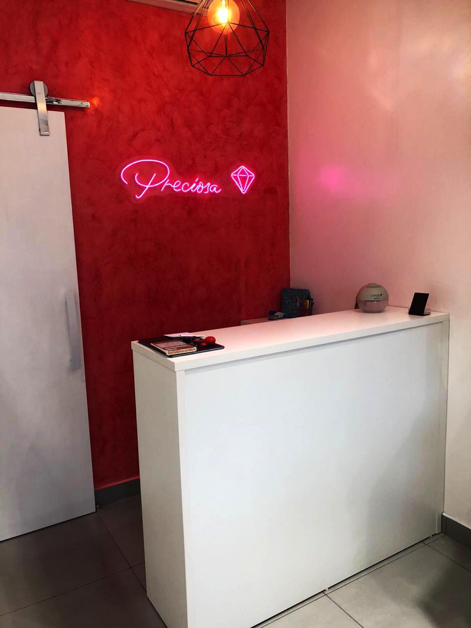 Recepção de salão de beleza com neon rosa em parede vermelha