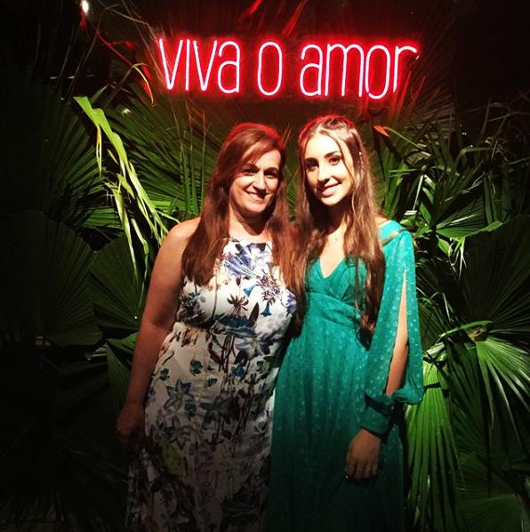 Convidadas em frente ao neon Viva o amor com folhagens
