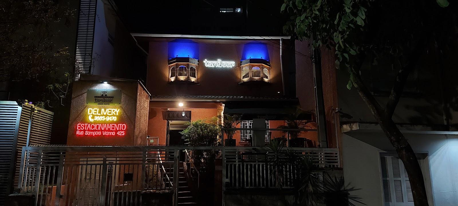 Fachada de restaurante à noite com letreiro de neon iluminado