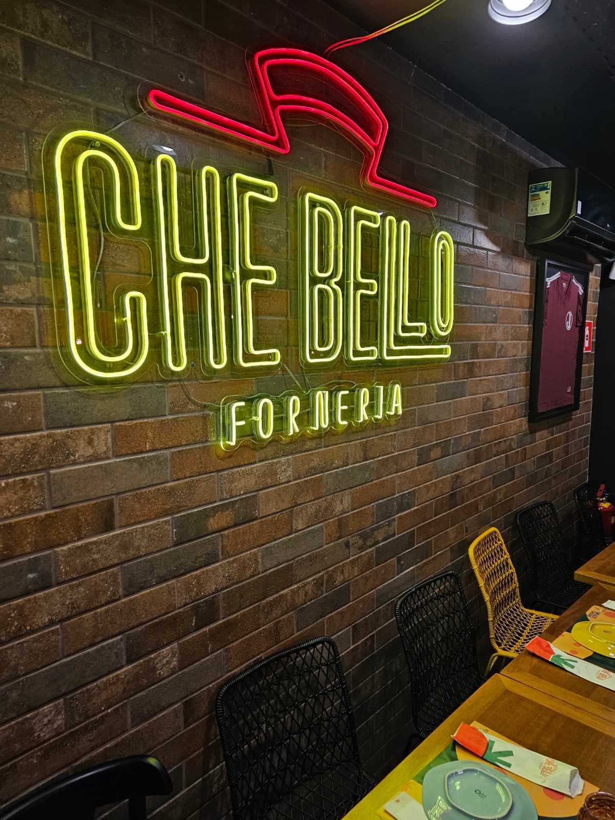Neon amarelo de forneria em parede de tijolo de pizzaria