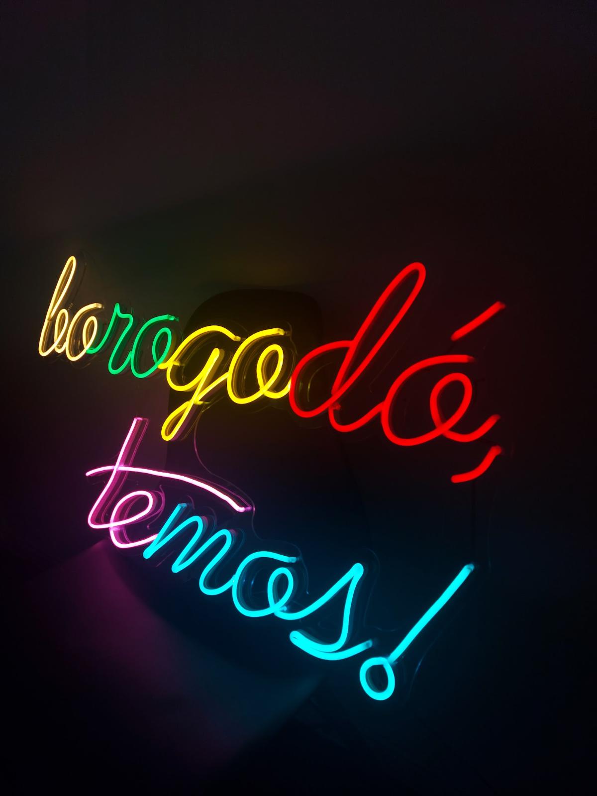 Neon colorido cursivo em parede escura de restaurante