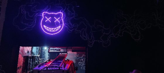 Letreiro de neon LED roxo em fachada noturna com grafite
