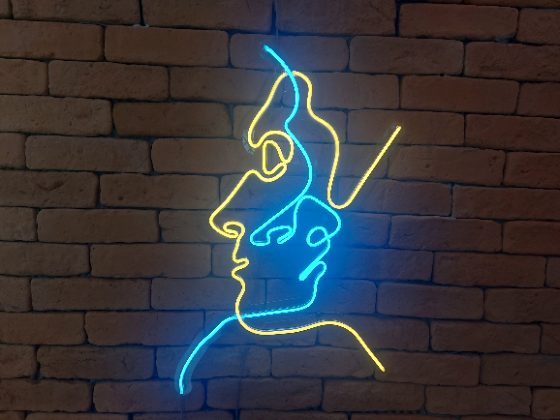 Dois perfis em traço contínuo de neon LED azul e amarelo sobre tijolo