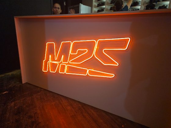 Logo em neon personalizado laranja aplicado em balcão de atendimento