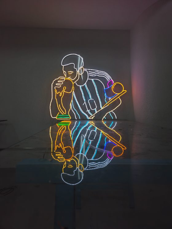 Peça artística de neon LED multicolorida sobre mesa de vidro